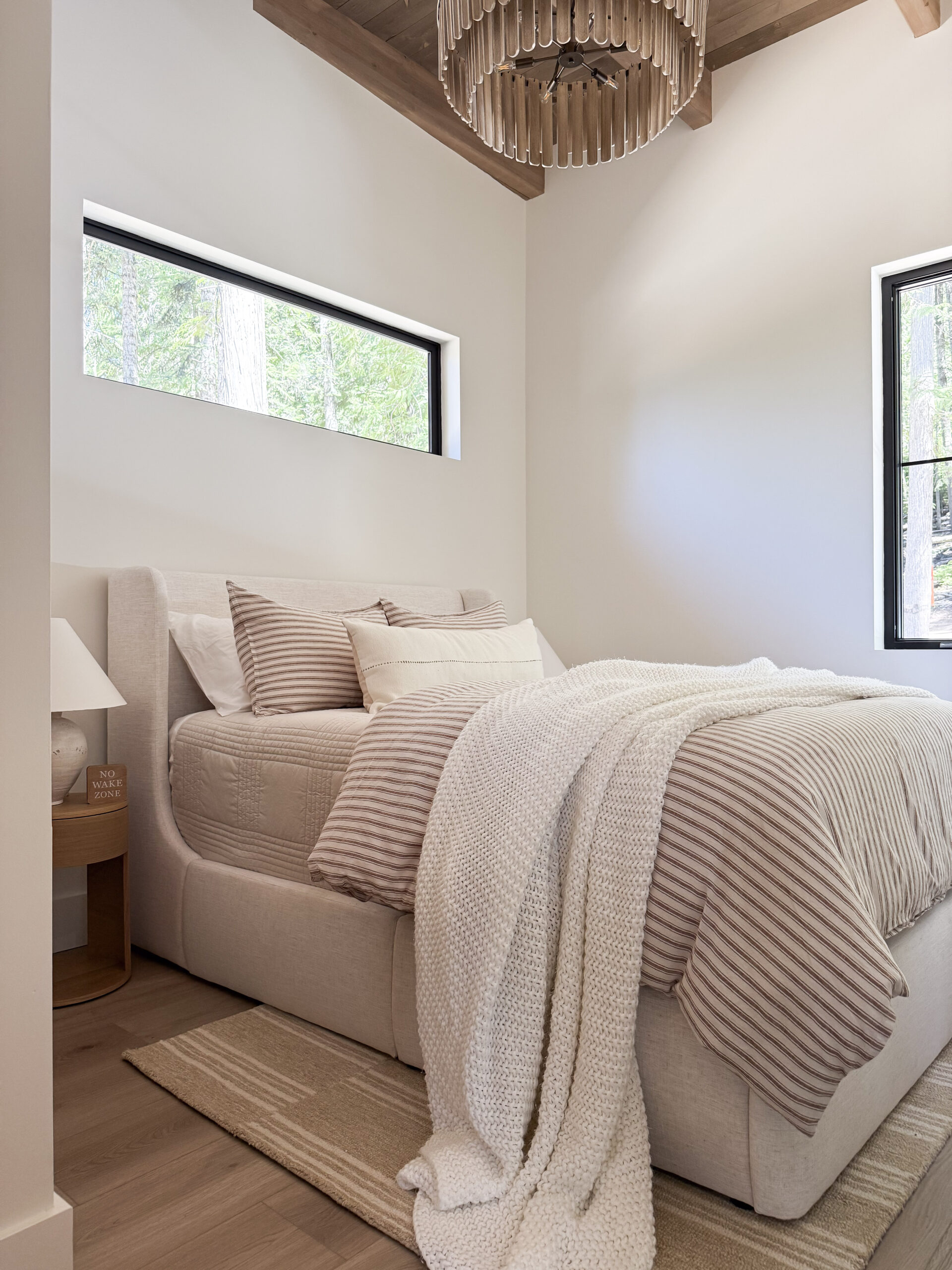 a photo featuring a bedroom with striped linens, a storage bed, and unique chandelier