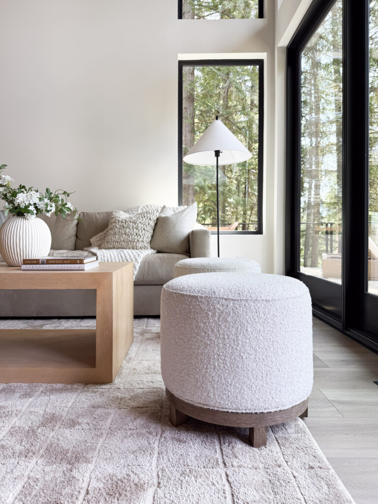 cabin decor essentials | a photo featuring a living room with a sofa, coffee table, vase faux florals, area rug, and swivel stool