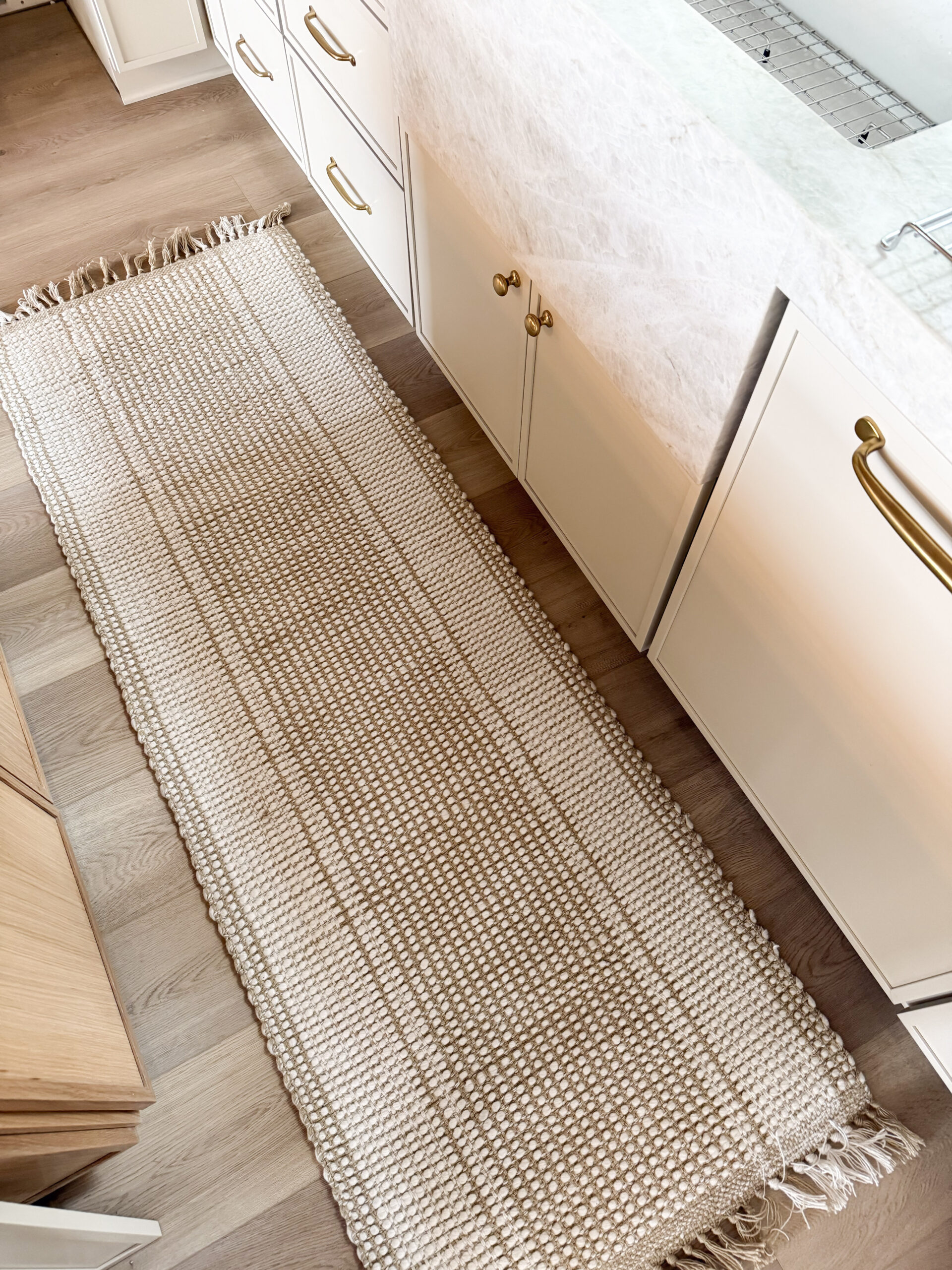 cabin decor essentials | a photo featuring a woven runner rug and vintage brass pulls and knobs in a kitchen