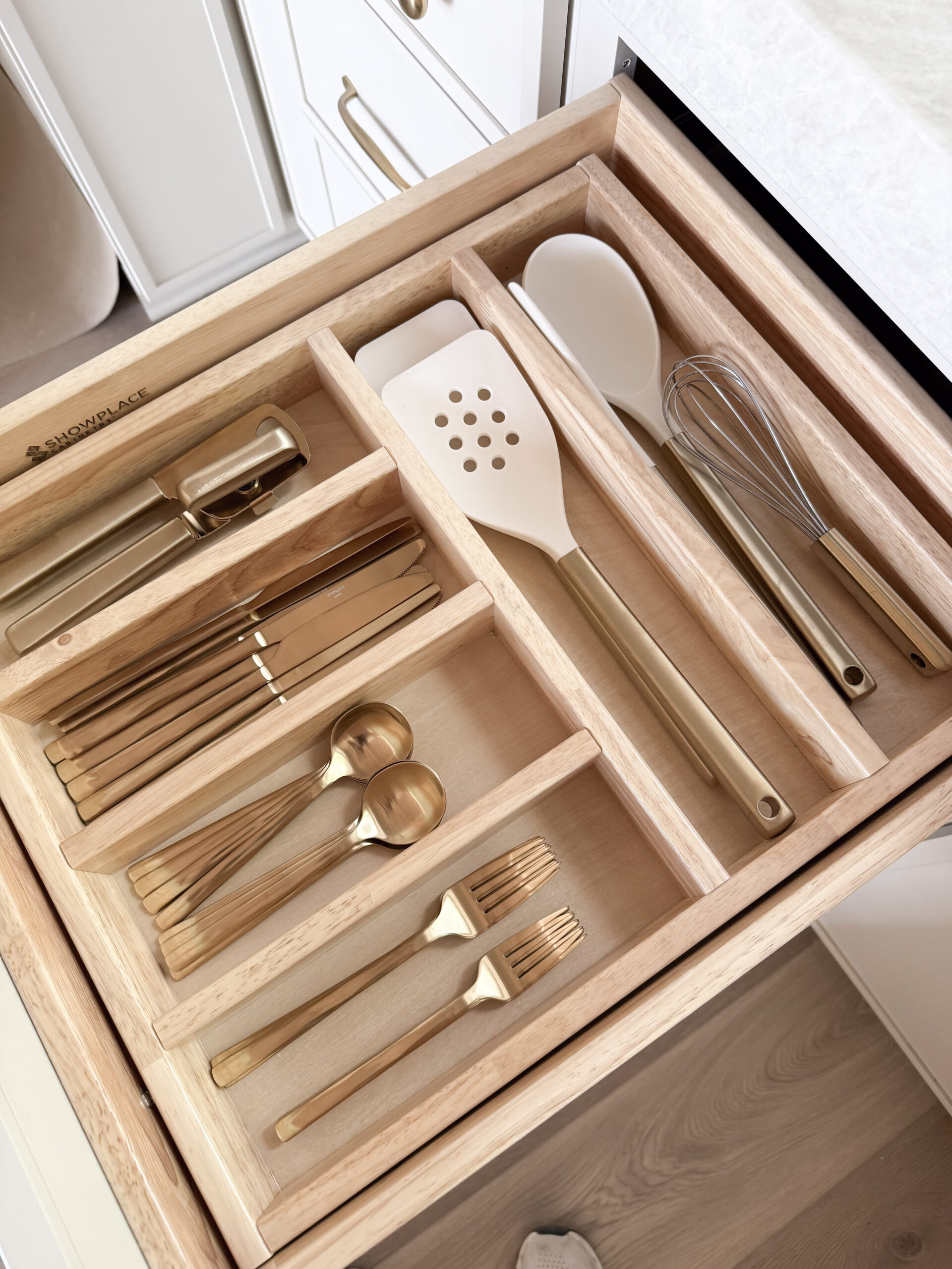 cabin decor essentials | a photo featuring a kitchen drawer organizer with gold flatware and champagne Figmint cooking utensils