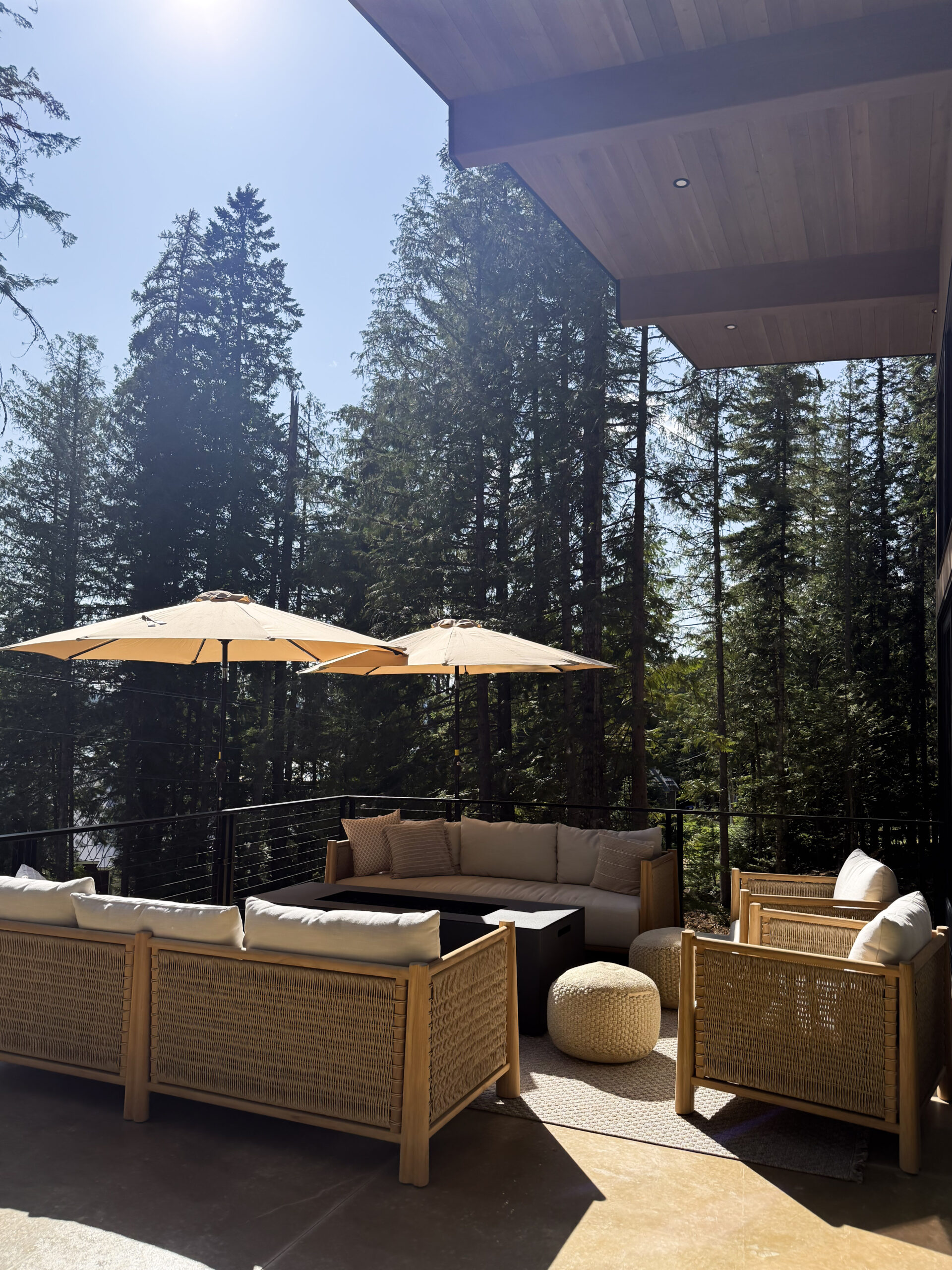 a photo featuring a patio space with solar umbrellas, outdoor sofa and lounge chair, pouf, and area rug