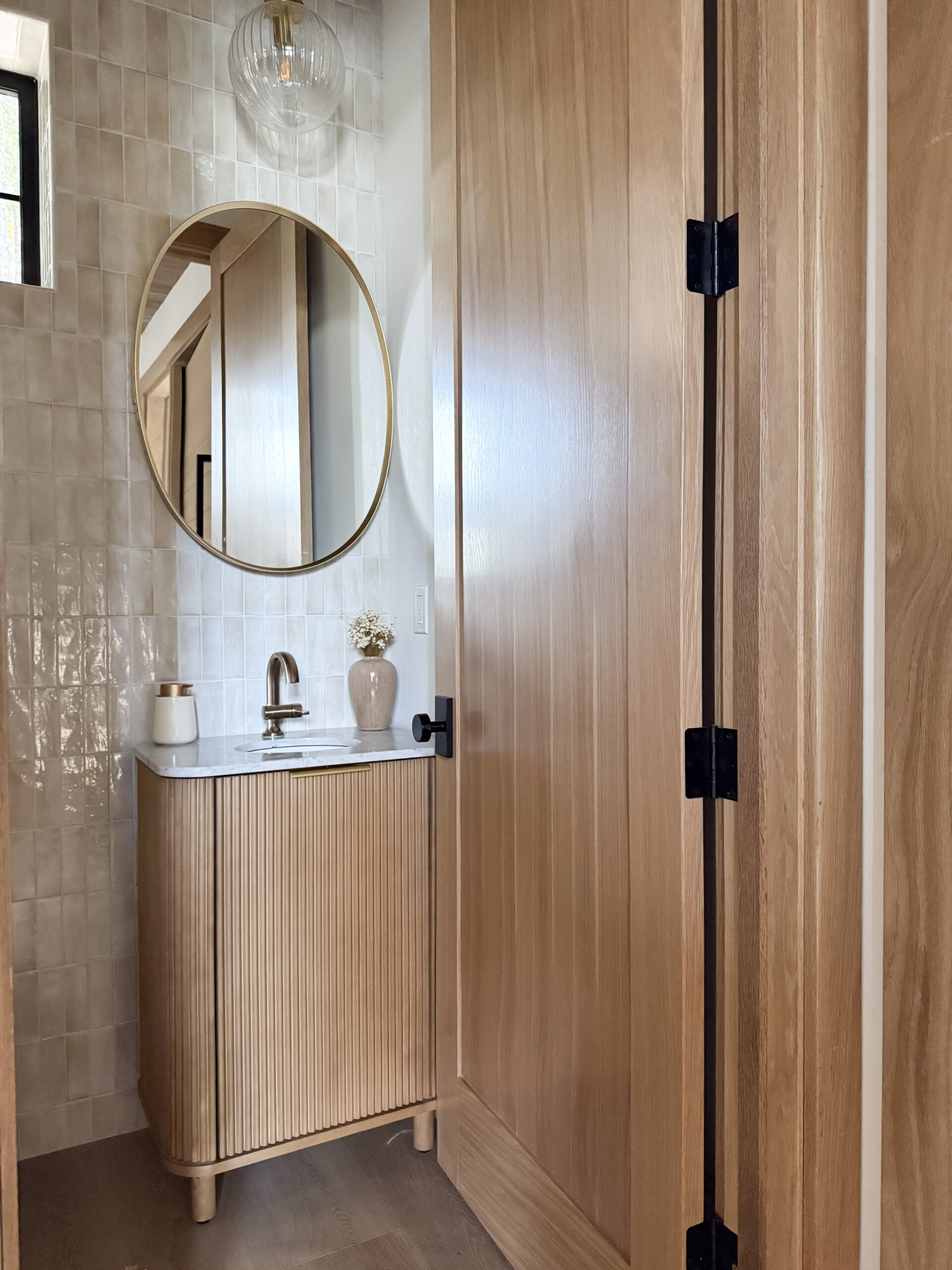 cabin decor essentials | a photo featuring a globe pendant light, oval medicine cabinet, soap dispenser, faux florals, and bathroom vanity