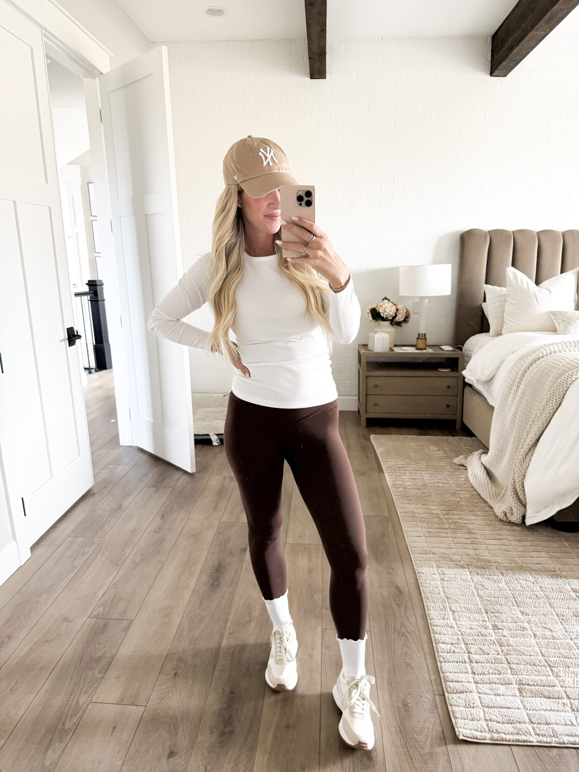 woman wearing long sleeve tee, leggings, ruffle socks, sneakers, and baseball cap