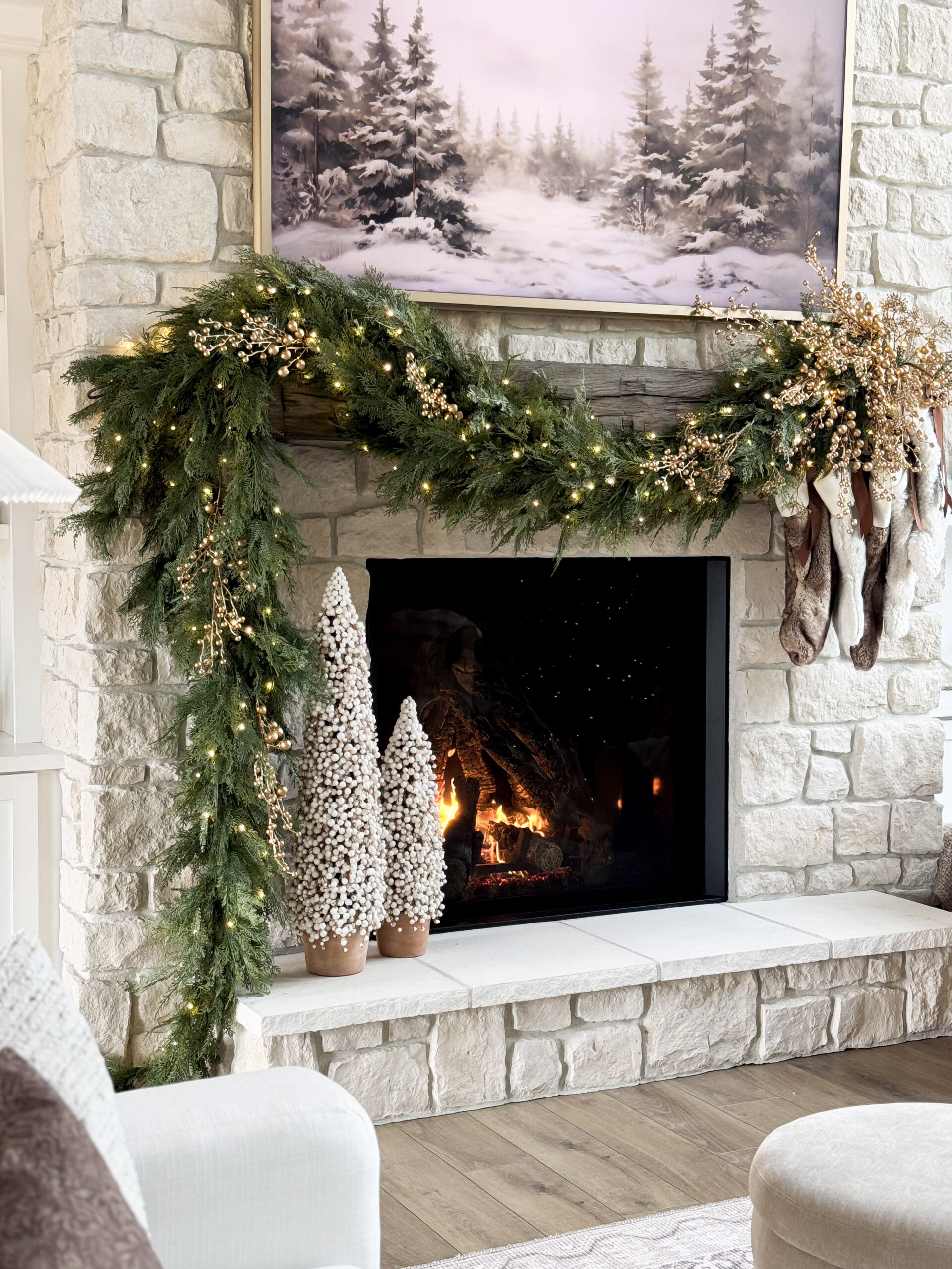 Mantel adorned with evergreen garland, hanging stockings, and warm holiday accents.
