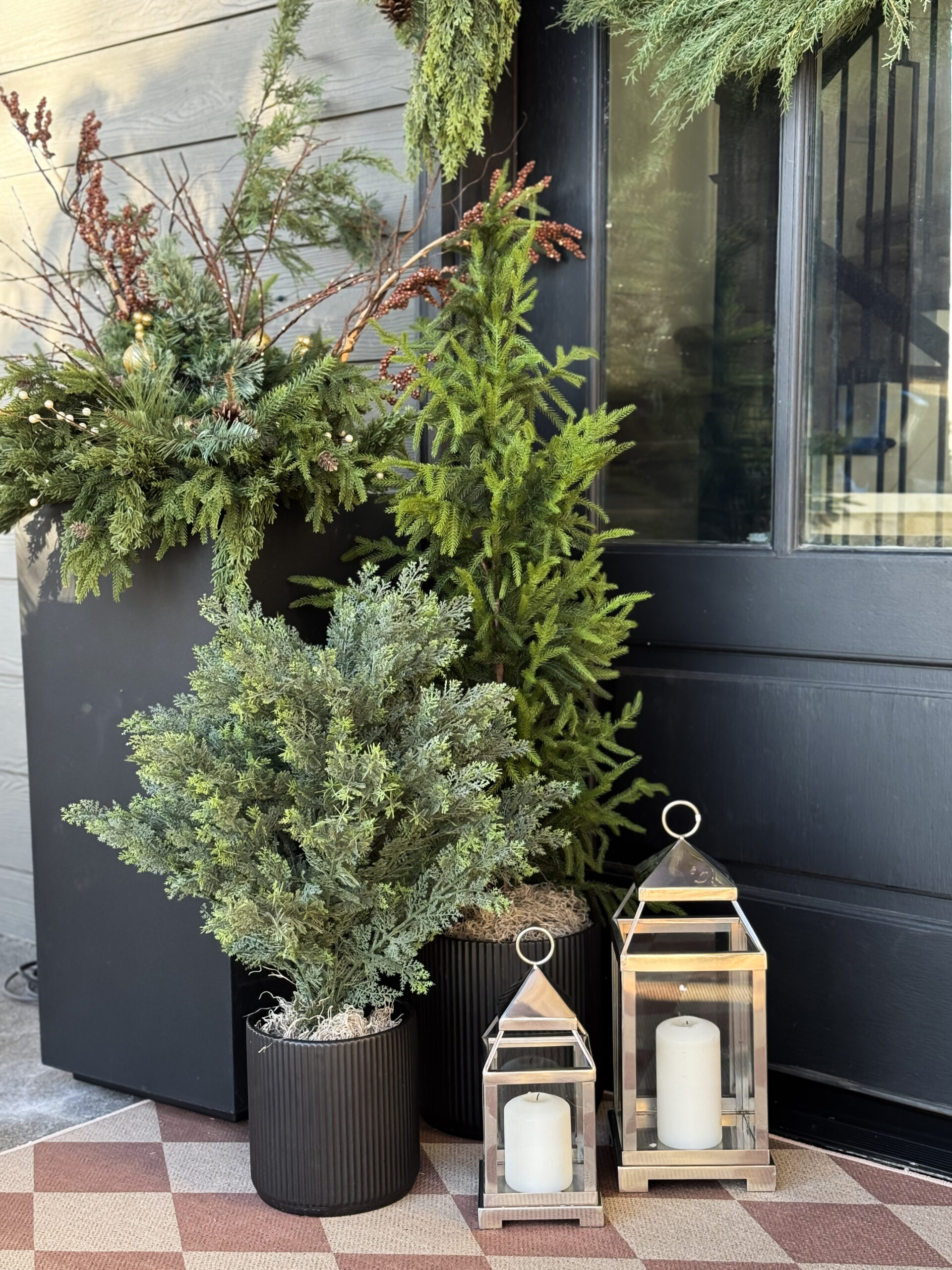 Front porch decorated with faux evergreen garland, lanterns, and holiday accents for a welcoming look.