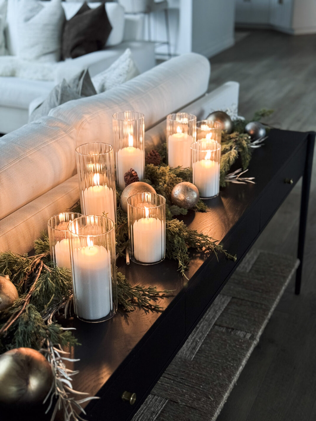 console table styled with pillar candles, greenery, and festive Christmas accents.