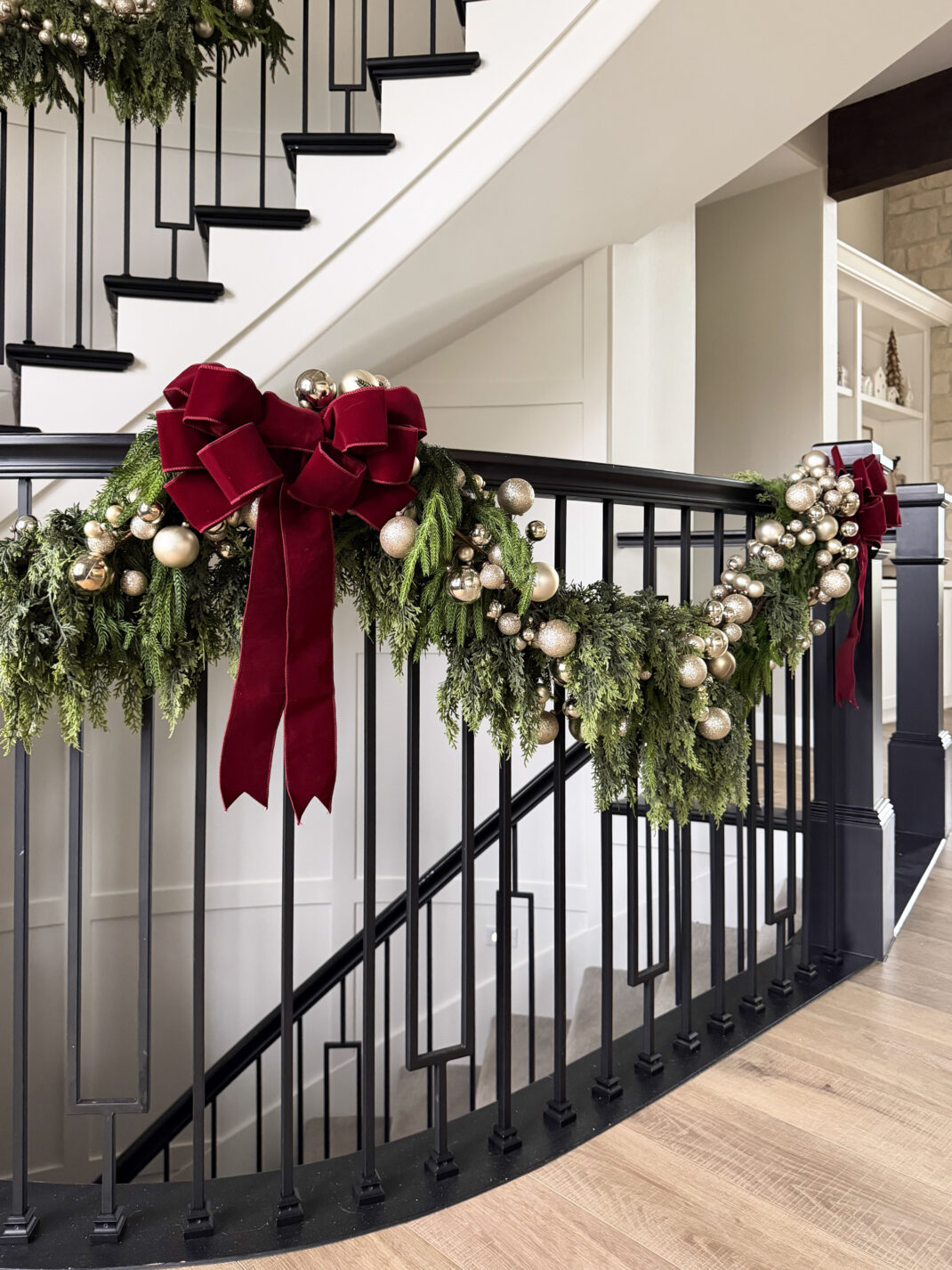 fluffy cedar garland on staircase with ornament garland and red bow