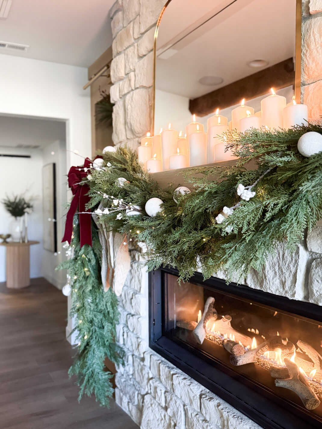 faux cedar garland on holiday mantel with twinkle lights, ornaments, and pillar candles