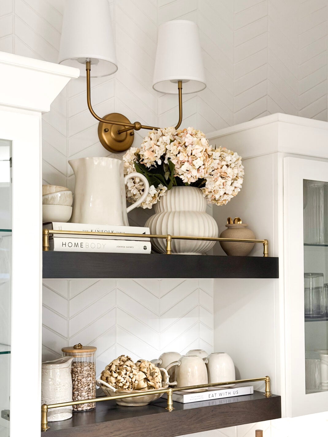 image of kitchen shelves with brass gallery rail and wall sconce