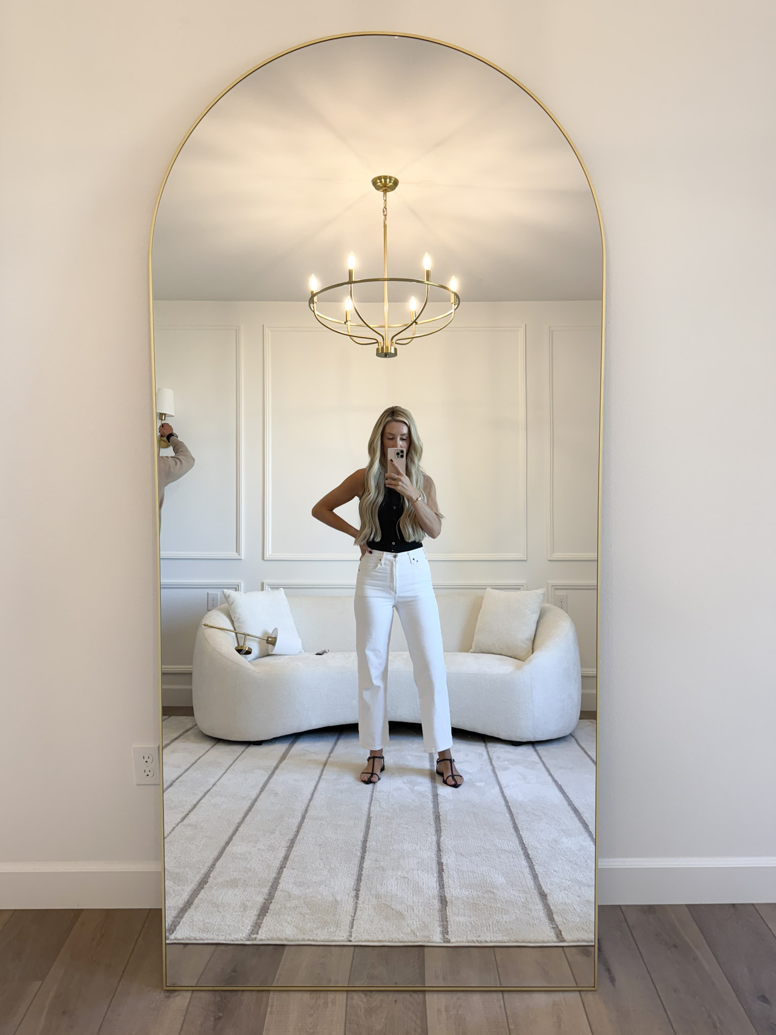 woman taking selfie in front of gold-trimmed floor-length mirror