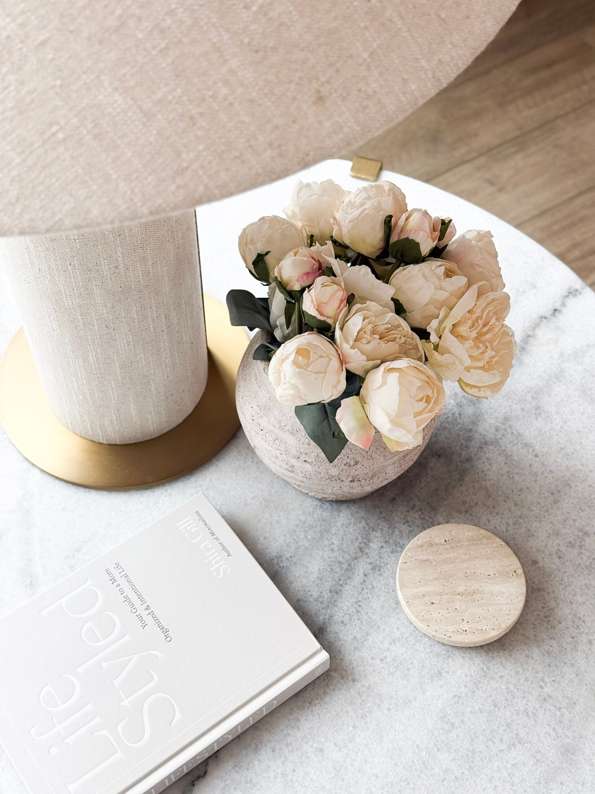 faux peonies in a vase on a side table