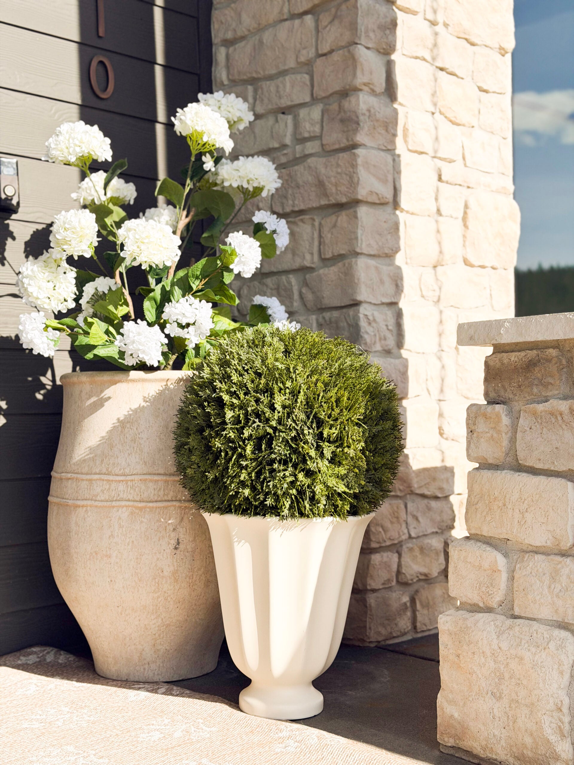 faux topiary and faux hydrangea in pots on a front porch